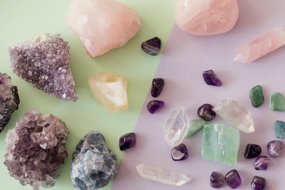 Amethyst, rose quartz, citrine and green calcite crystals scattered across a sage green and lavender surface